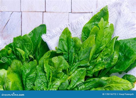 Freshly Harvested Spinach On A White Towel Stand On White Wooden Table