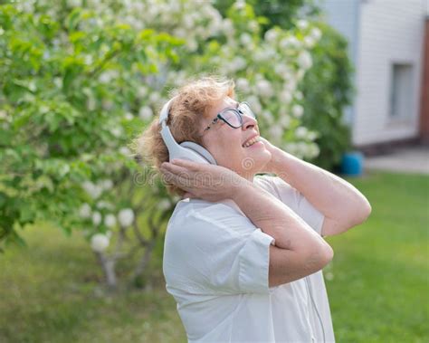 An Elderly Caucasian Woman Walks In A Park And Listens To Music A