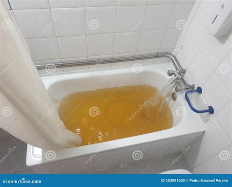 Bathtub Full Of Yellow Water Due To Rust Or Impurities Stock Photo