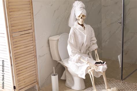 Skeleton in bathrobe with mobile phone sitting on toilet bowl Stock ...