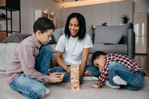 Heureuse famille afro américaine assise sur le sol et jouant au jenga