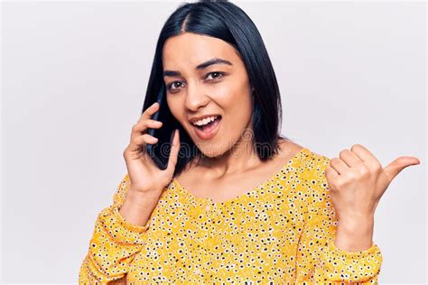 Jovem Linda Latina Conversando No Smartphone Apontando O Polegar Para O Lado Sorrindo Feliz