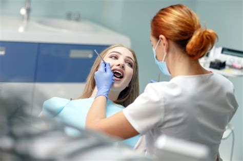 Dentista Feminina Verificando Os Dentes Do Paciente Foto Premium