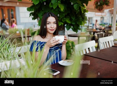 Gorgeous Brunette Girl Sitting On The Table In Cafe With Cup Of Coffee And Drink Stock Photo Alamy