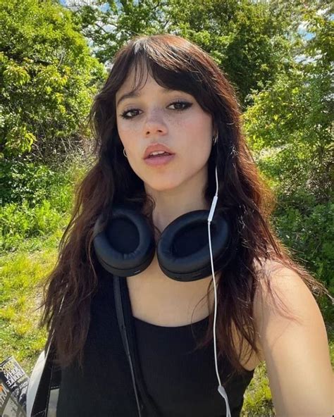 A Woman Wearing Headphones Standing In Front Of Trees