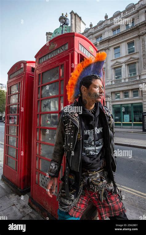 Punk rocker with mohican hair sits relaxing on top of red telephone ...