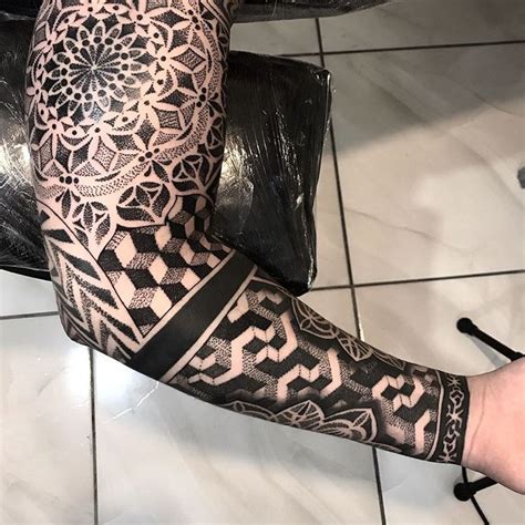 A Man S Arm And Leg Covered In Black Ink With An Intricate Design On It