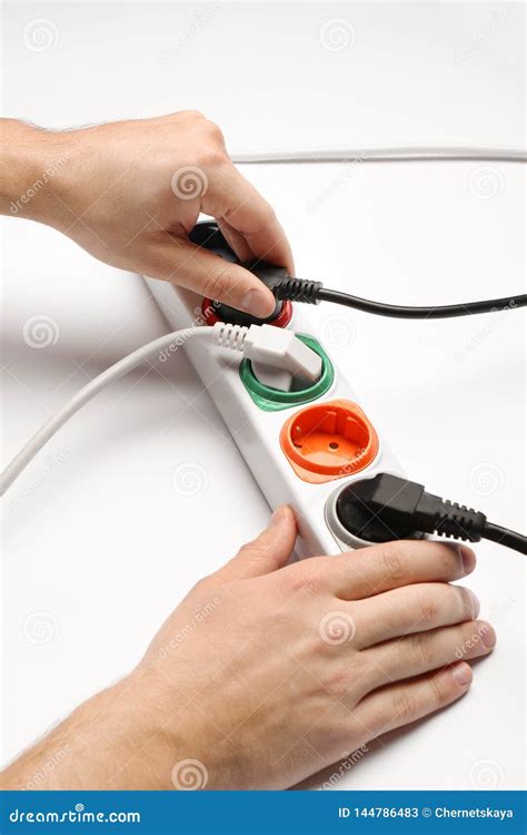 Man Inserting Power Plug Into Extension Cord On White Background