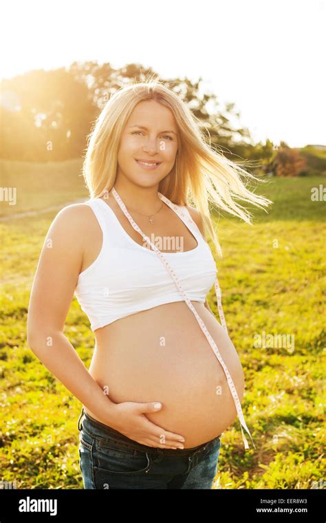 Beautiful Blond Pregnant Woman Standing In The Summer Park In Sunshine