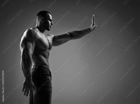 Side View Of Strong Muscular Man Half Naked Shirtless Athlete Sportsman Stands Holding Arm