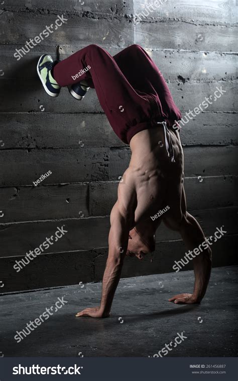 Athlete With Naked Torso Doing Push Ups On His Hands While Standing Upside Down Near The