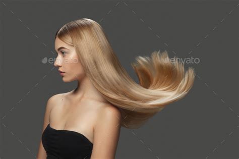 Beautiful Model With Long Smooth Flying Blonde Hair Isolated On Dark