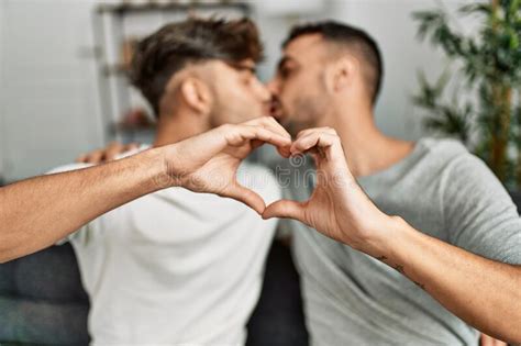 Two Hispanic Men Couple Kissing And Doing Heart Shape With Hands At