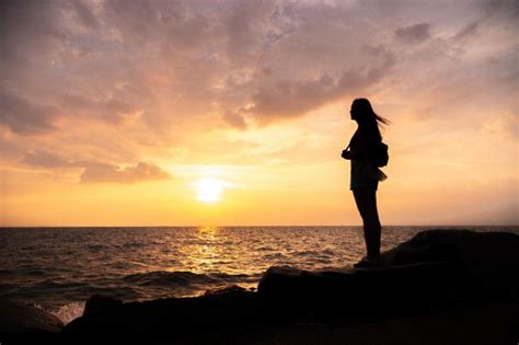 Situación de la mujer de la silueta cielo de la puesta del sol sobre