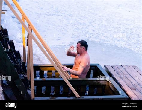 A Man Is Crossing Hinself While Submerging In The Ice Cold Water As