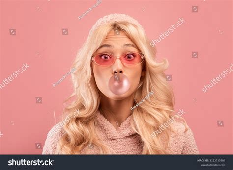 2 Joyful Blonde Lady Chewing Gum And Blowing Bubble Looking At Camera On Pink Studio Images