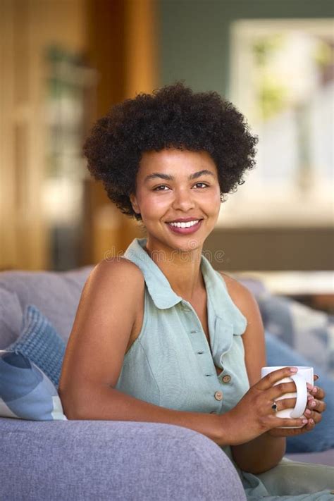 Portrait Of Smiling Woman Relaxing On Sofa At Home Holding Hot Drink Stock Photo Image Of