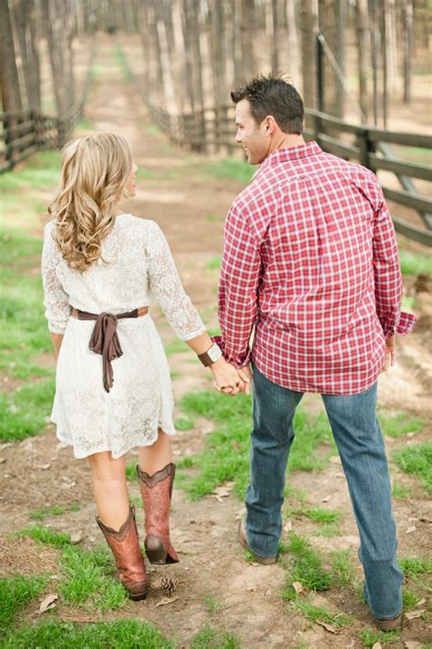 A Man And Woman Holding Hands While Walking Through The Woods