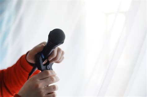 Встаньте с микрофоном. мужчина держит за руки микрофон на штативе ...