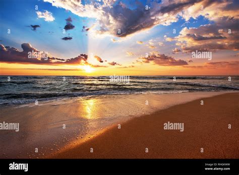 Colorful Ocean Beach Sunrise With Deep Blue Sky And Sun Rays Stock