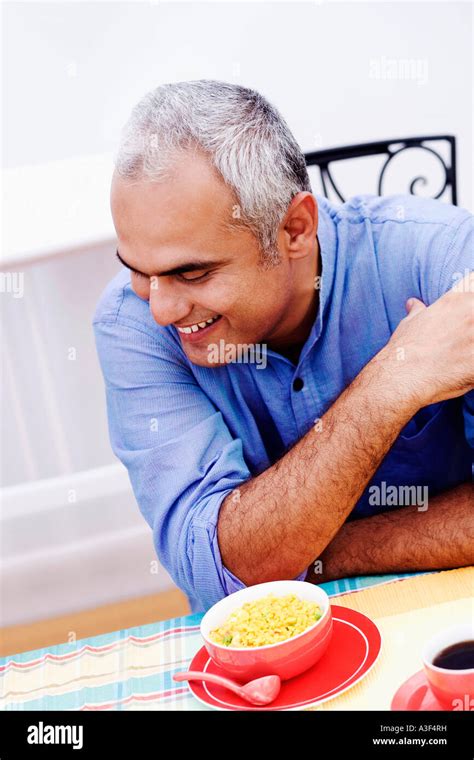 Mid Adult Man Sitting At A Table And Smiling Stock Photo Alamy