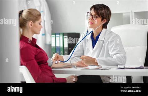 Positive Female Doctor Checking Pulse Of Woman Patient Using