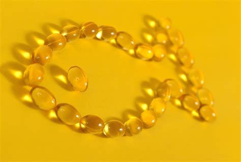 Капсулы с рыбьим жиром омега-3 в форме рыбы на желтом фоне | Премиум Фото