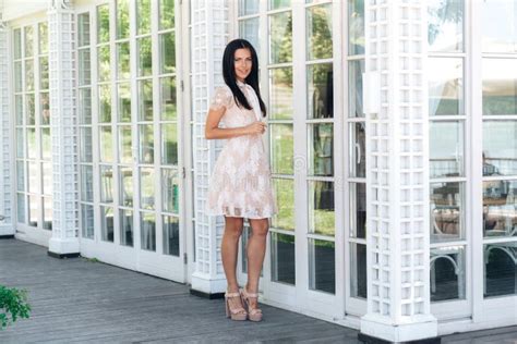 Cute Brunette With Beautiful Long Legs Posing In Beige Colour Dress Outside Near A Wooden And