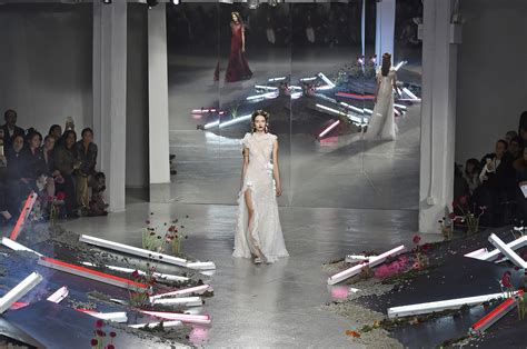 a model walks down the runway in a white gown