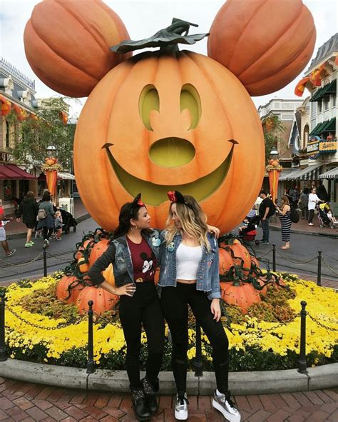 Two Women Standing Next To Each Other In Front Of A Mickey Mouse