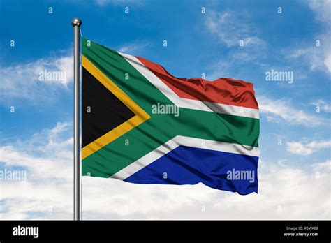 Flag Of South Africa Waving In The Wind Against White Cloudy Blue Sky