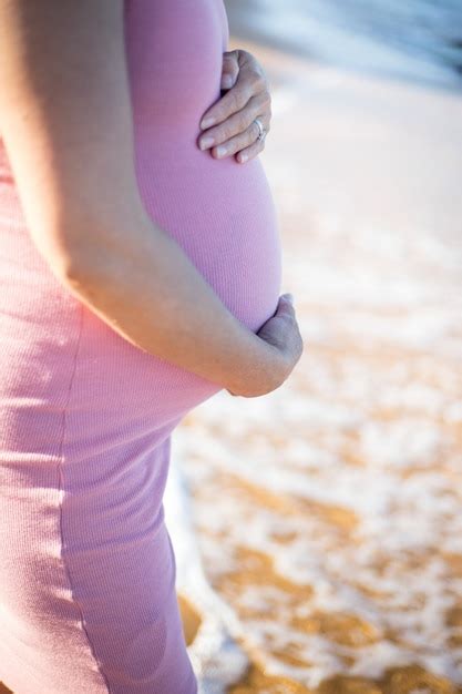 Premium Photo Pregnant Belly In Pink Dress With Hands Holding And Sea And Sand Beach In