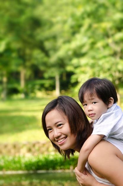 Retrato De Una Madre Feliz Dando Un Paseo A Su Hijo En El Parque Foto