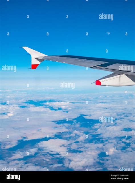 British Airways Airbus 319 plane wing seen from plane window during flight above bank of white ...