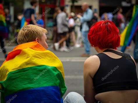 Dos mujeres jóvenes en el orgullo gay de París 2022 vistas por detrás con una con la bandera del