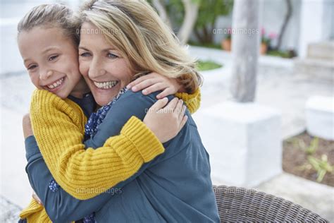 Enthusiastic Grandmother And Granddaughter Hugging On Patio 11086031402