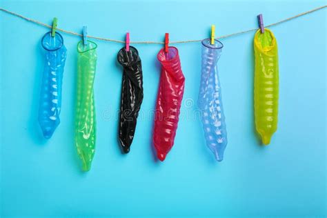 Used Colorful Condoms Hanging On Clothesline Against Blue Background Safe Sex Concept Stock