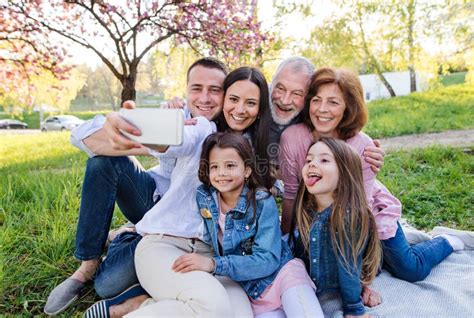 Familia De Tres Generaciones Sentada Afuera En La Naturaleza De