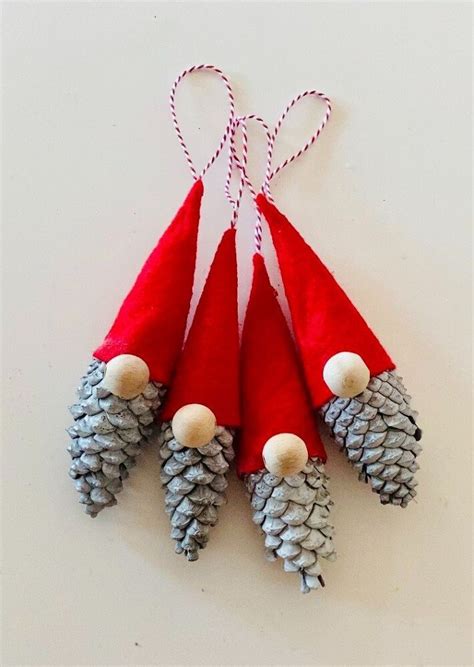 Three Pine Cones With Red And White Hats Hanging From Twine On Top Of