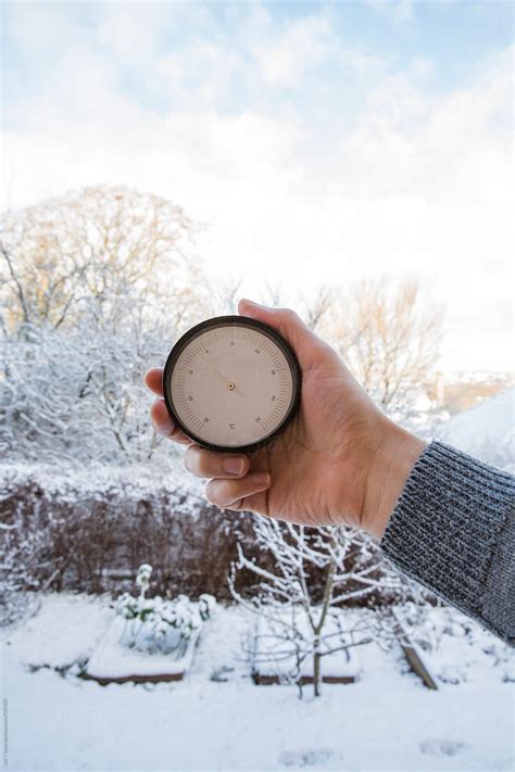 "Hand Holding Thermometer Measuring Temperature Outside" by Stocksy