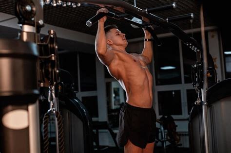 Premium Photo Handsome Sporty Guy Trainer With Tanned Muscular Naked Torso Pulls Up In The Gym