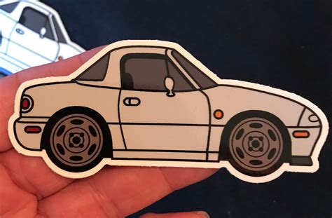 A Hand Holding A White Sticker With A Car On It