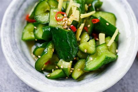 A White Bowl Filled With Cucumbers And Topped With Sesame Seeds