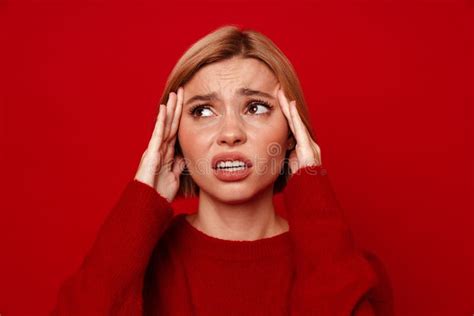 Unhappy Blonde Woman With Headache Rubbing Her Temples Isolated Over Red Wall Stock Image