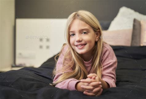Blonde Girl Lying On The Bed Smiling Looking At The Camera Stock Photo By Retamosastock