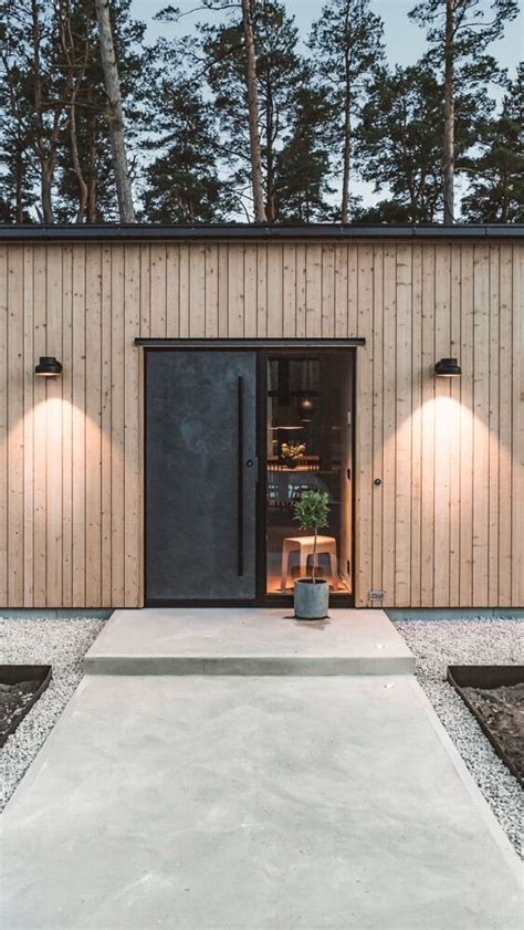 The Entrance To A Modern House With Two Lights On It S Side And An Open