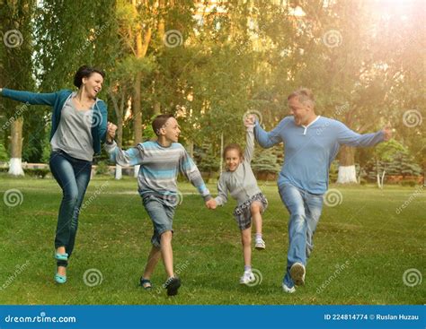 Feliz Familia Joven Corriendo En El Parque De Verano Foto De Archivo