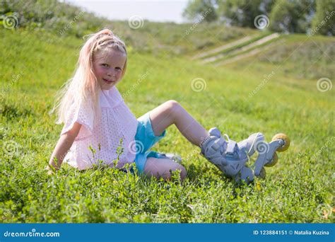 Petite Fille Blonde Mignonne S Asseyant Sur L Herbe Verte Et Mettant