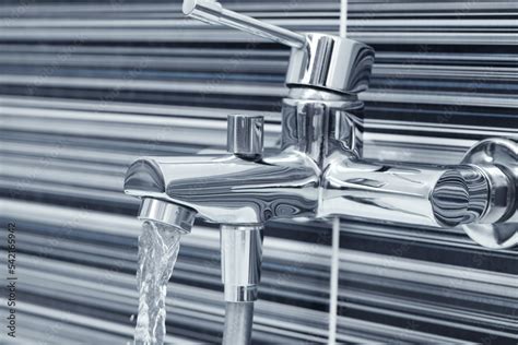 Water Flowing From Bath Tap Installed On Black And White Wall Stock