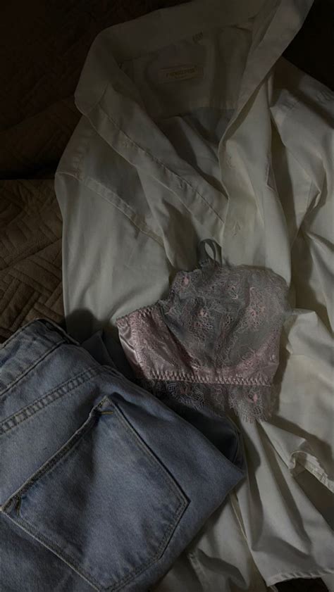 An Unbuttoned Shirt And Jeans On A Bed